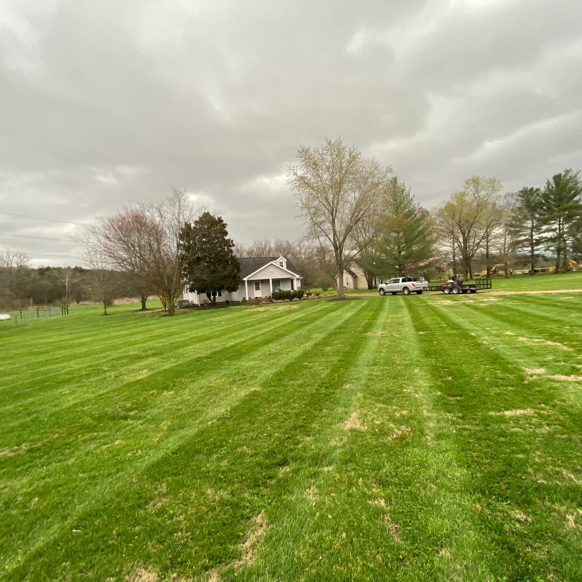 Pickup truck and mower trailer at a freshly striped country property